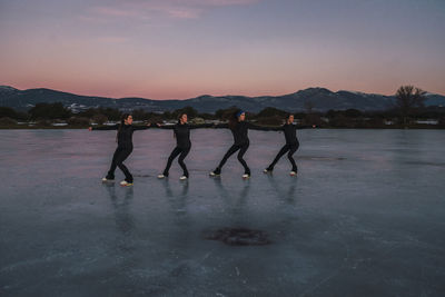 Female figure skaters practicing on frozen lake at dusk