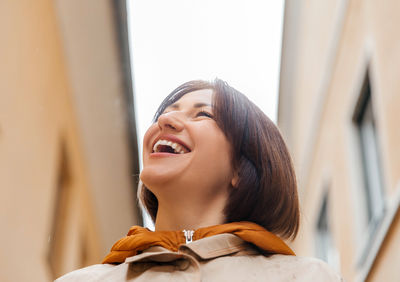 Upward gaze of a smiling young woman in an urban alley