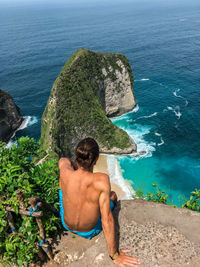 Rear view of shirtless man looking at sea