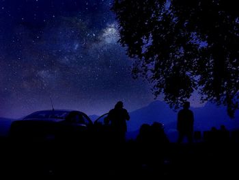 Low angle view of silhouette people on field against sky at night