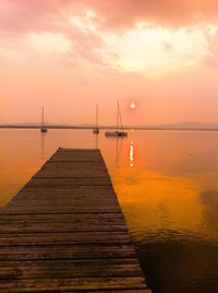 Jetty in lake against sky during sunset