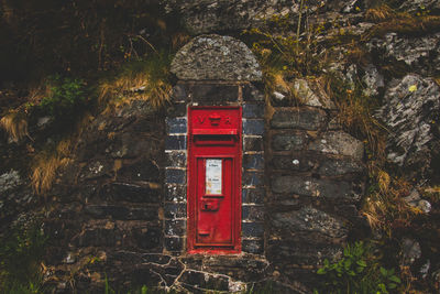 Close-up of red mailbox on rock against trees