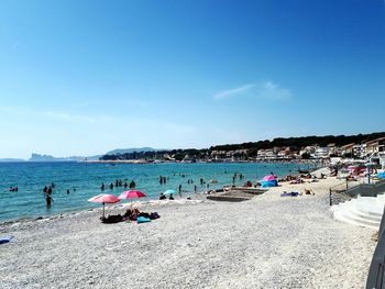 People on beach against blue sky