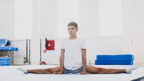 Full length of teenager boy stretching at home