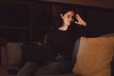 Young woman sitting on sofa at home