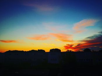 Silhouette of building against cloudy sky at sunset