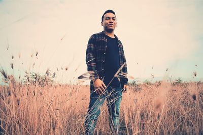 Young man standing on field against sky