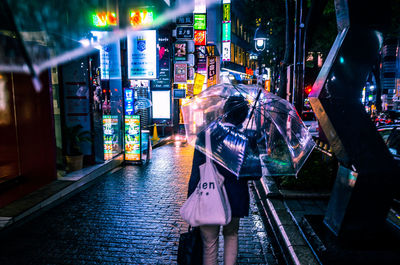 Rear view of woman walking on illuminated street