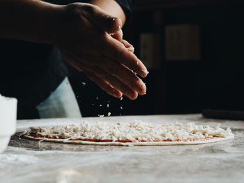 Midsection of man preparing pizza at table in home