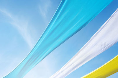 Low angle view of colorful fabrics against sky