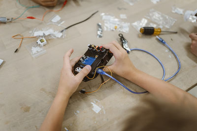 High angle view of student examining electrical component on table at school workshop