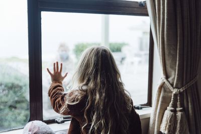 Rear view of woman against window