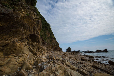 Rock formations on shore against sky