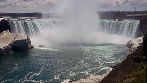 Scenic view of waterfall against sky