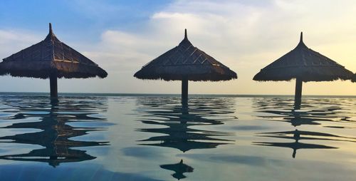 Stilt houses in sea against sky