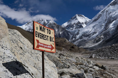 Information sign on snowcapped mountains against sky