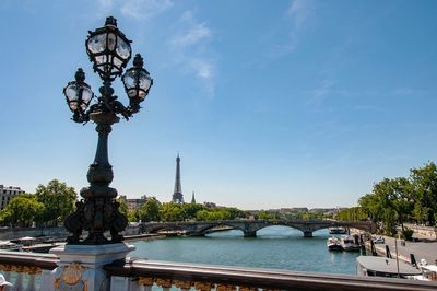 Street light by river against blue sky