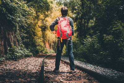 Rear view of man walking on railroad track
