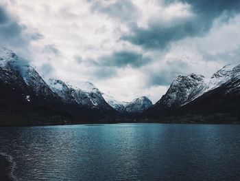 Scenic view of mountain by lake against cloudy sky