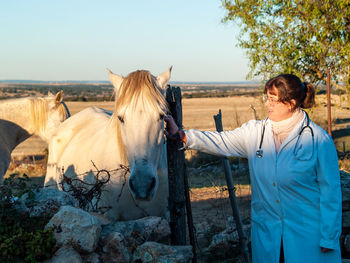 Doctor touching horse on field