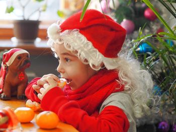 A little girl in a santa claus hat, in a new year's costume, joyfully greets the new year, 