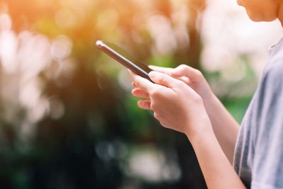 Midsection of woman using mobile phone outdoors