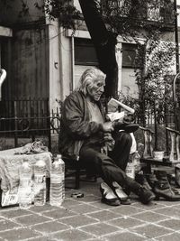 Homeless man sitting on footpath in city