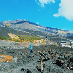 Rear view of man standing on mountain against sky