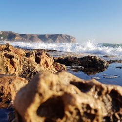 Scenic view of rocks on beach against clear sky