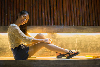 Woman looking away while sitting on floor