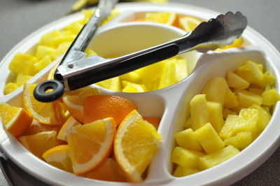 Close-up of fruits in container with serving tongs on table