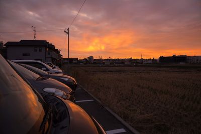 Cars on field against sky during sunset