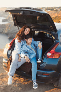 Portrait of smiling woman sitting on car