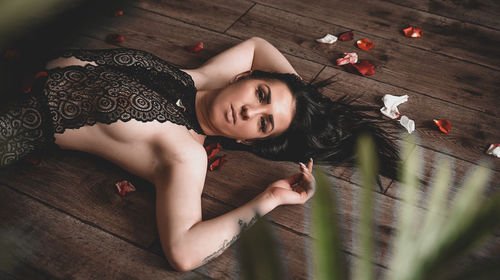 Portrait of sensuous woman lying down on wooden floor