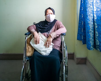 Portrait of a senior woman wearing hijab on wheelchair in a hospital.