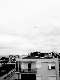 Birds flying over city against sky