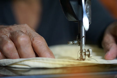 Cropped hands of person sewing at sewing machine