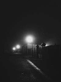 Illuminated road against clear sky at night