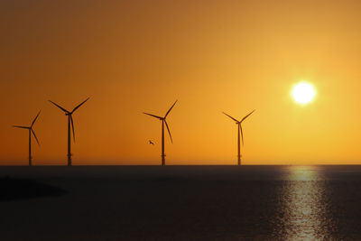 Silhouette wind turbine against sky during sunset