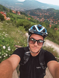 High angle portrait of teenage boy wearing sunglasses and cycling helmet on mountain