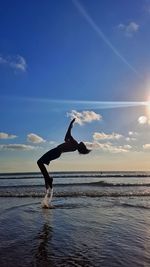 Full length of man jumping against sea and sky