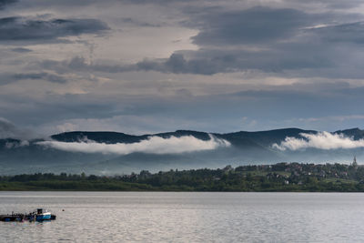 Scenic view of sea by mountains against sky