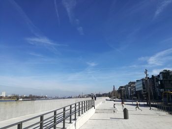 View of footpath by river against blue sky