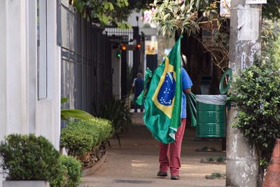 Full length of man standing by plants in city with a flag