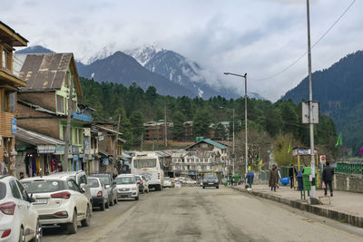 Vehicles on road by mountain against sky