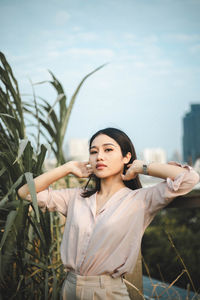 Young woman standing on field against sky