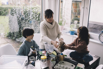 Woman separating waste with children at home