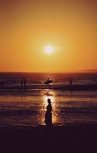 Silhouette people on beach against sky during sunset