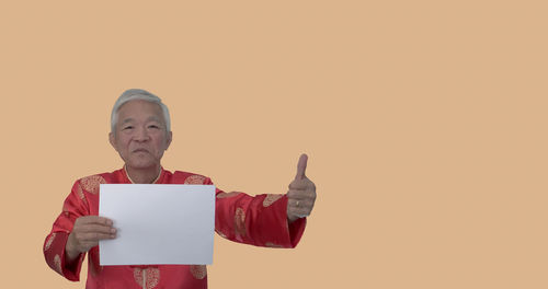 Portrait of man standing against red background