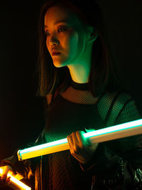 Young woman looking away while standing against black background